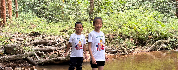 Two Primrose Hill children standing near a stream